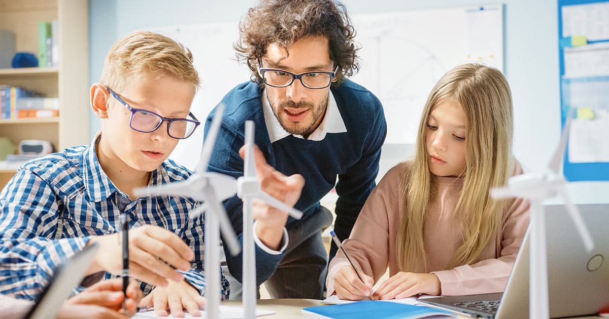 Teacher showing students scale model windmills